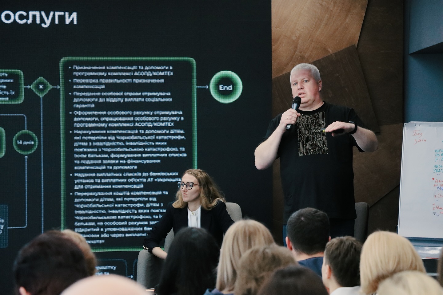 Чоловік у чорному одязі розповідає щось у мікрофон.